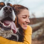 Cachorro e mulher sorrindo ao ar livre