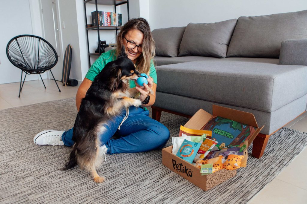 Tutora e seu cachorro sentado na sala de sua casa se divertindo com o BOX.Petiko